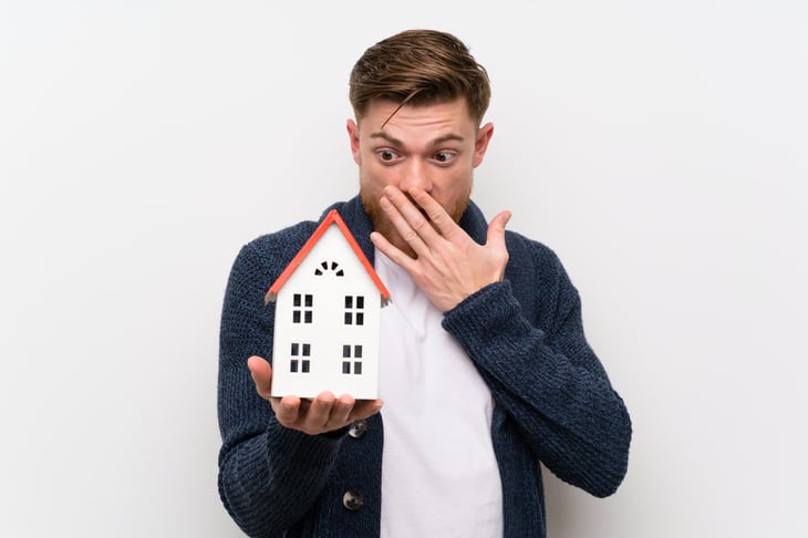 Worried man holding small house