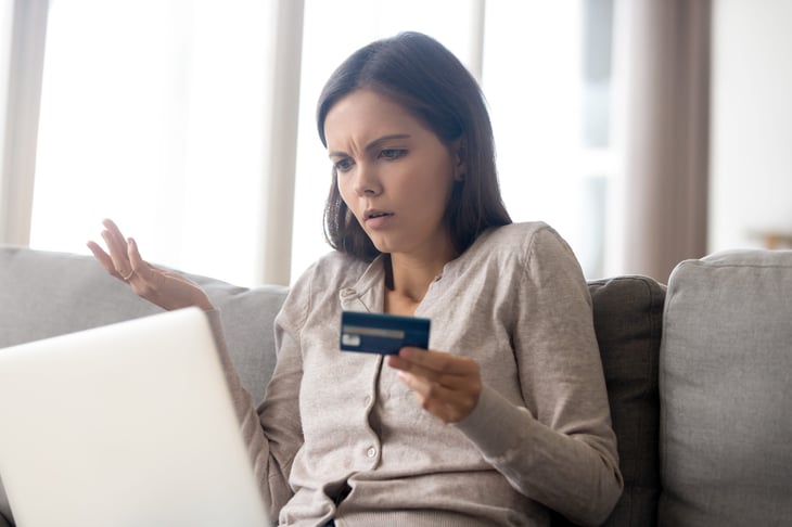 Frustrated woman with credit card on laptop