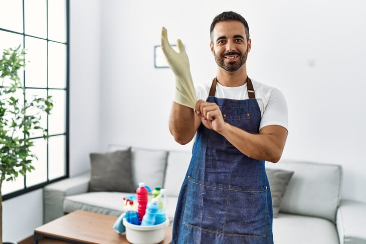 man smiling confident wearing apron and cleaning gloves at home
