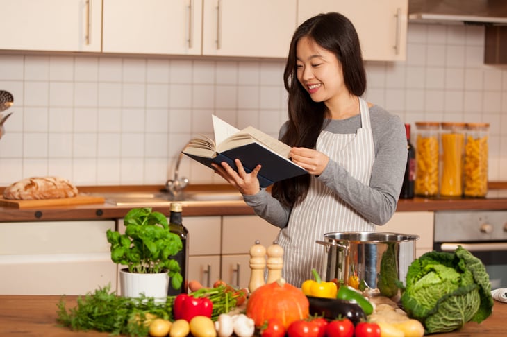 Woman reading a cookbook in her kitchen