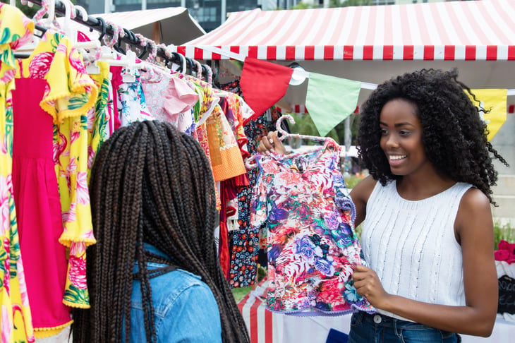 Two women at a yard sale look at clothing