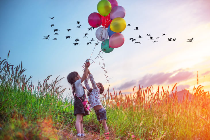 girls holding balloons in field