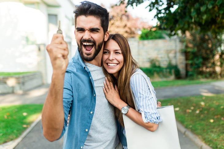 Happy couple standing in front of their new home.