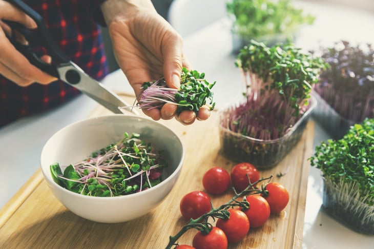 Woman making a salad with microgreens