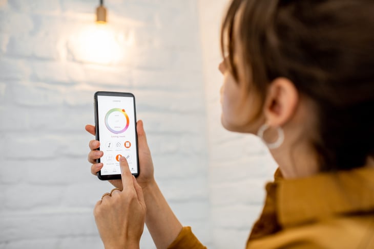 Woman using a smartphone app to control a smart lightbulb