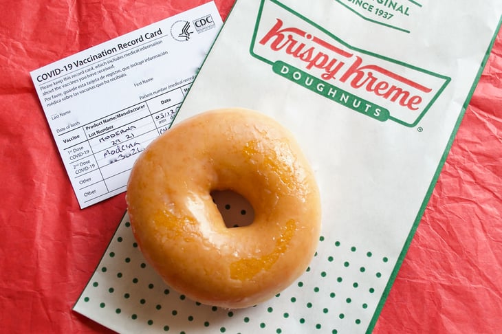 A free Krispy Kreme Original Glazed Doughnut next to a COVID-19 vaccination card