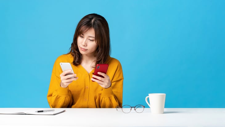 Woman comparing two phones or mobile phone plans