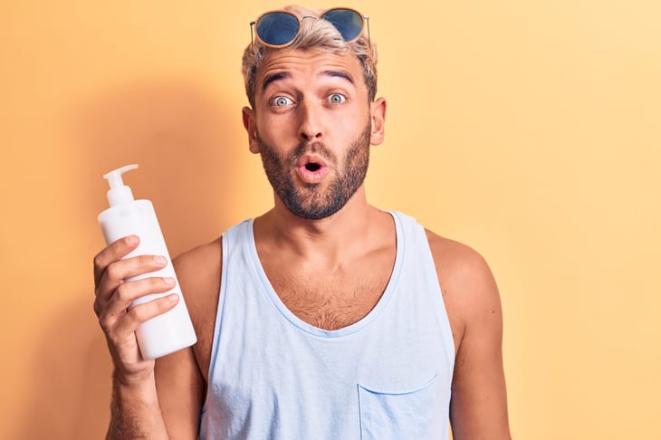Man holding a bottle of sunscreen