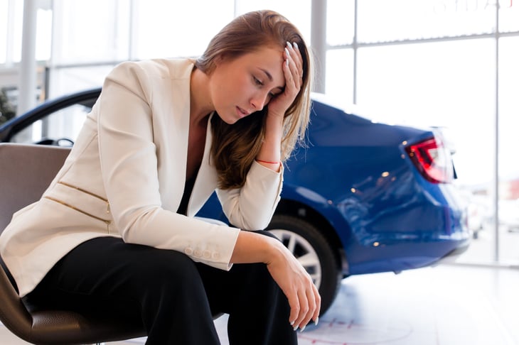 Upset woman sitting in car dealership