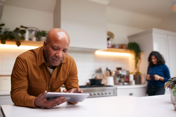 Man using a tablet computer in his kitchen while cooking