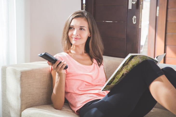 Woman reading magazine and watching TV