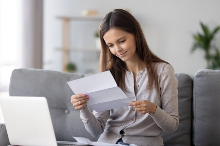 Smiling woman reviews her bills and student loan paperwork
