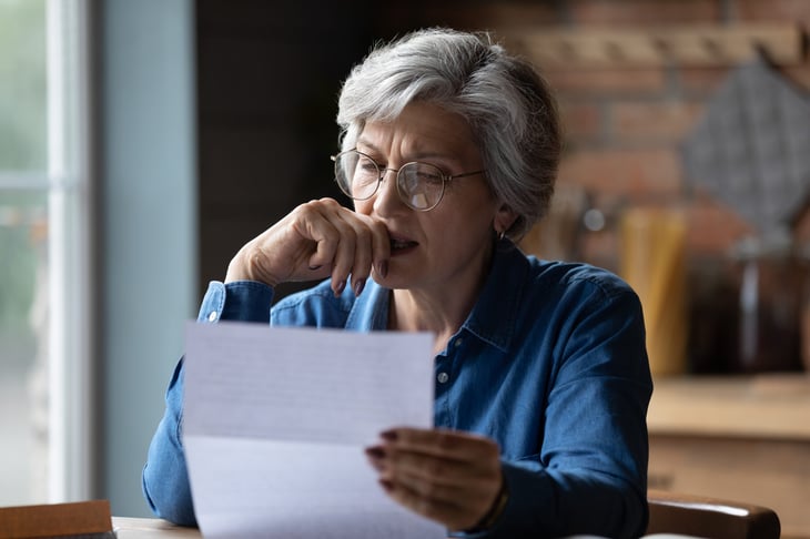 Upset senior holding a financial document