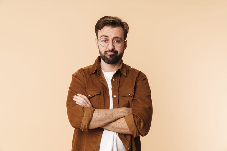 Skeptical, frustrated man with glasses and folded arms