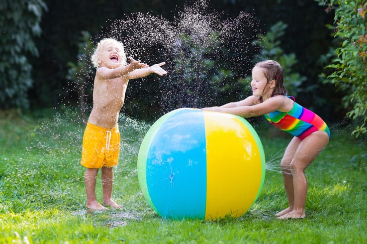 Children playing in a sprinkler on a summer day