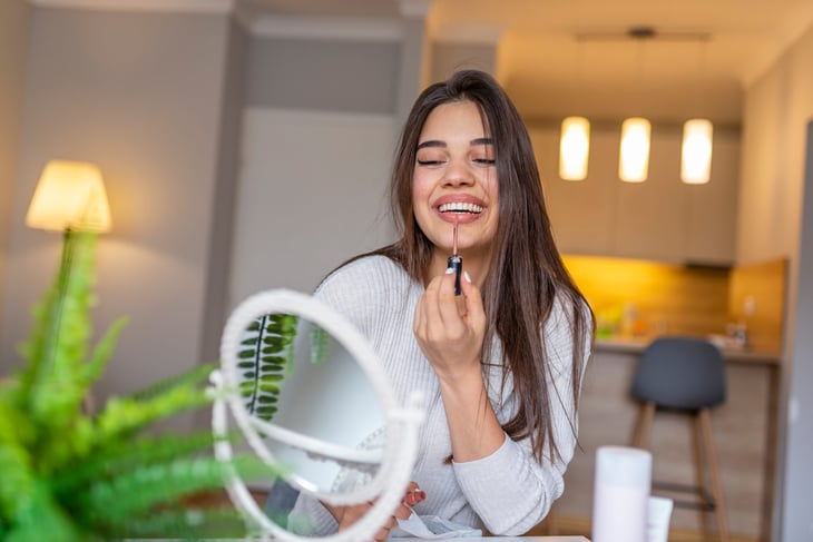 Woman putting on lipstick
