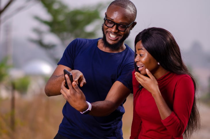 Man showing woman his great cellphone service on his smartphone