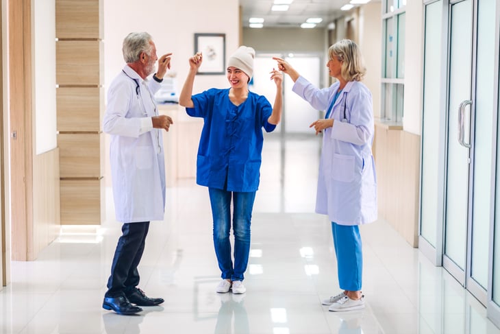 Doctor and nurse celebrating with a cancer survivor patient