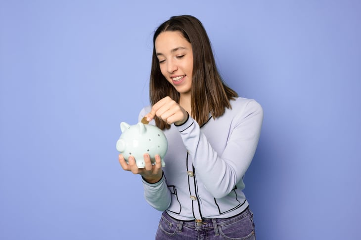 Young woman putting money in piggy bank