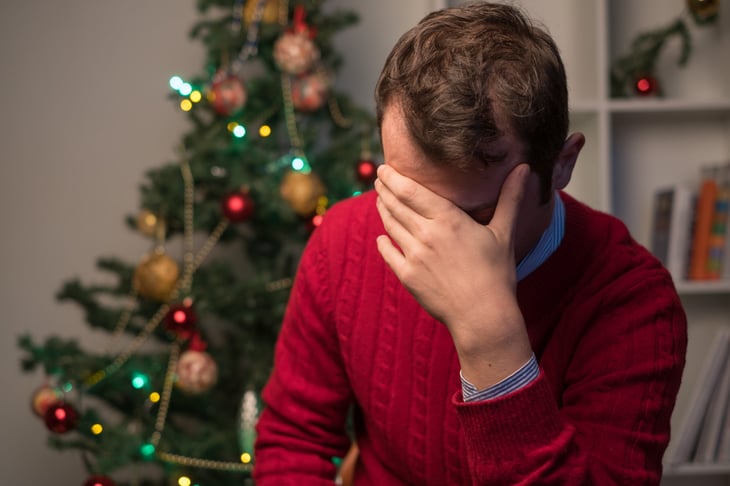 Sad man next to a Christmas tree