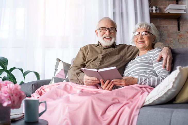 cozy senior couple on couch reading a book