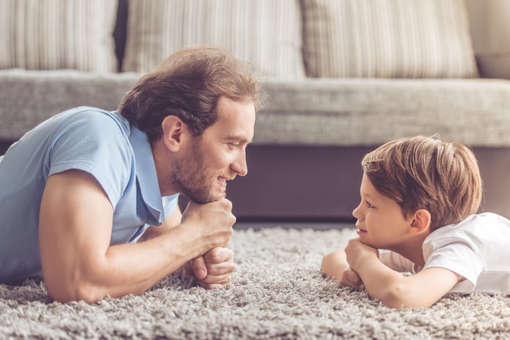Father and son smiling at each other on the floor