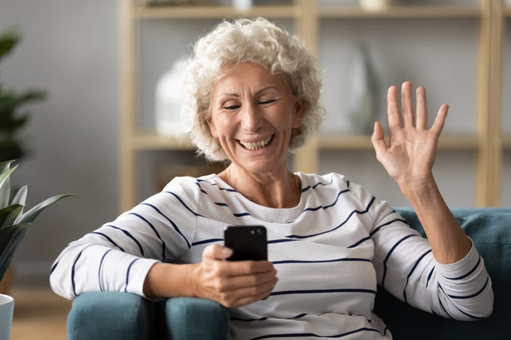 Senior woman waves goodbye to her phone