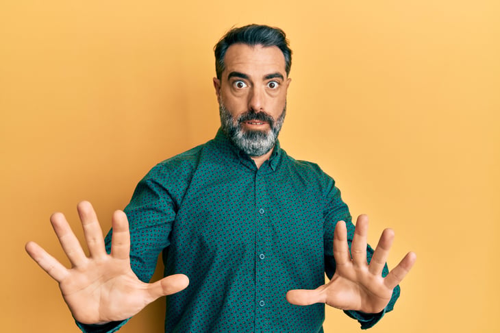 Worried middle aged man saying "Whoa" or "Stop" with hand motions and a concerned expression