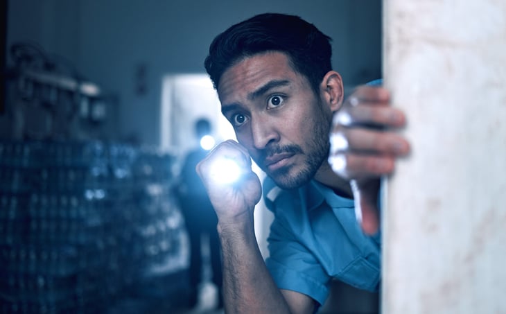 Nervous or scared man with a flashlight exploring a dark and creepy house