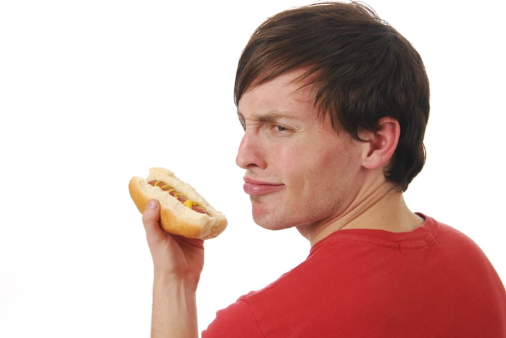 Unhappy man eating a hot dog