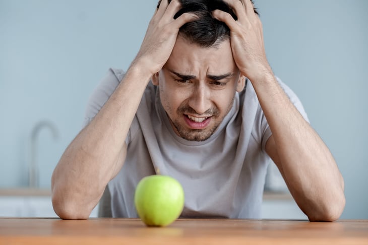 Unhappy man looking at an apple