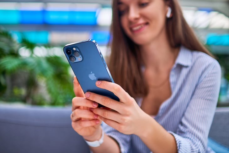 Woman smiling and using iPhone smartphone