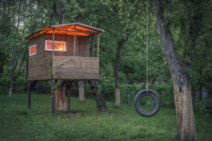 A treehouse and tire swing in a backyard
