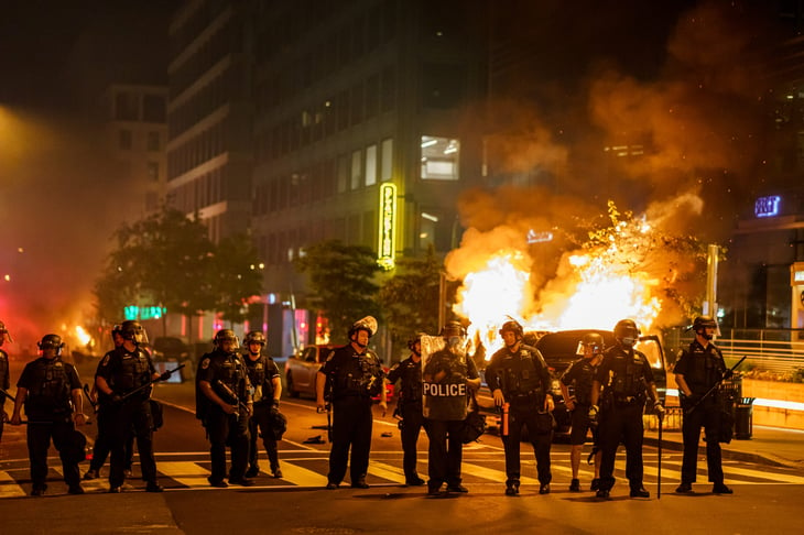 Police line in front of a burning car during a riot or protest