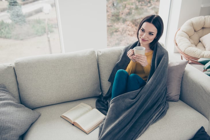 Woman wrapped in a blanket on her sofa