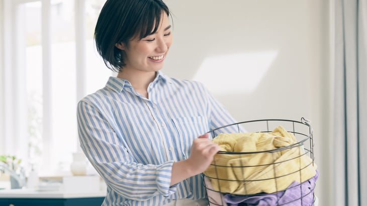 Happy woman holding a laundry basket