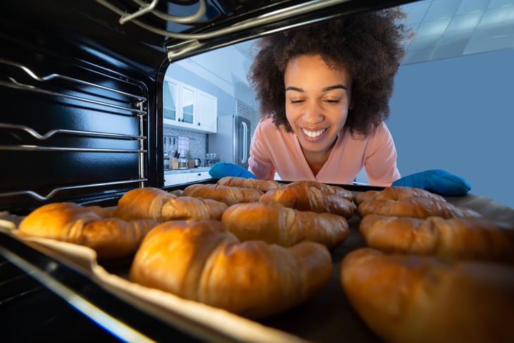 Happy woman baking croissants in her oven
