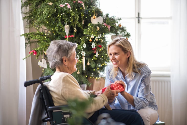Woman giving a Christmas gift to a senior in a wheelchair