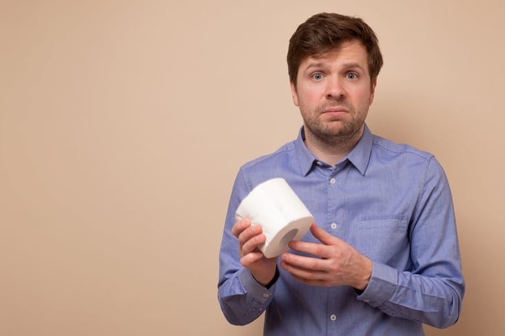Worried man holding a roll of toilet paper