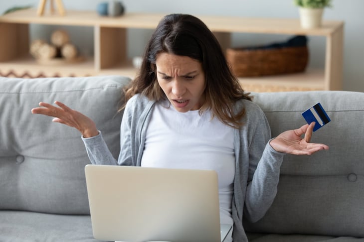 Woman frustrated with online shopping and holding a credit card