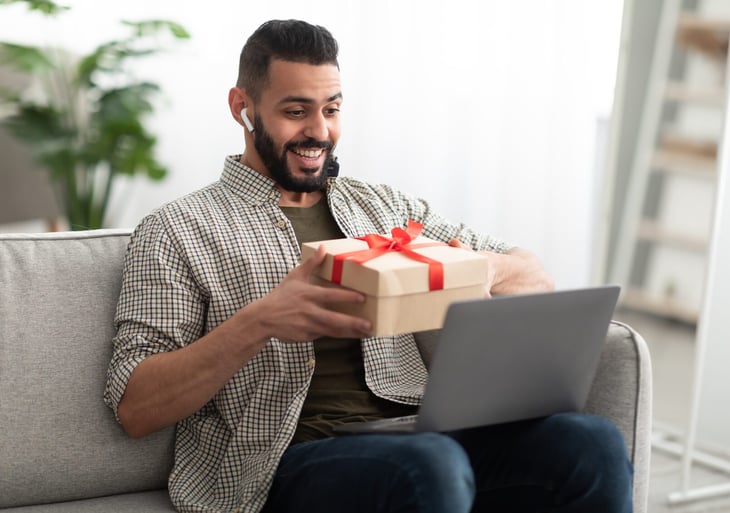 Man opening a holiday gift while on a video call