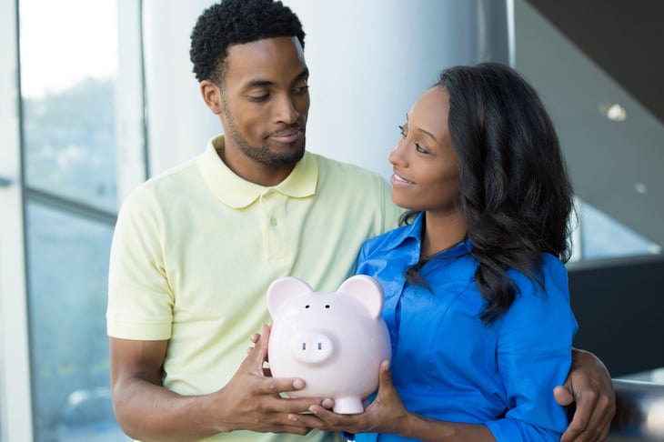 A satisfied couple holds a piggy bank for their investment in an IRA