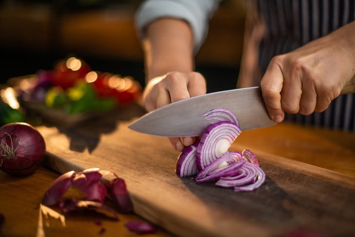 Woman chopping onions with a chef's knife