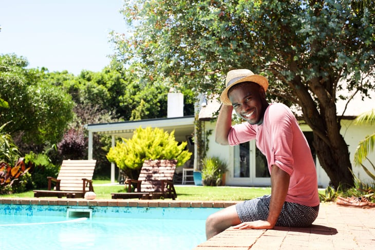 Happy man soaking in the sun at the pool outside his house