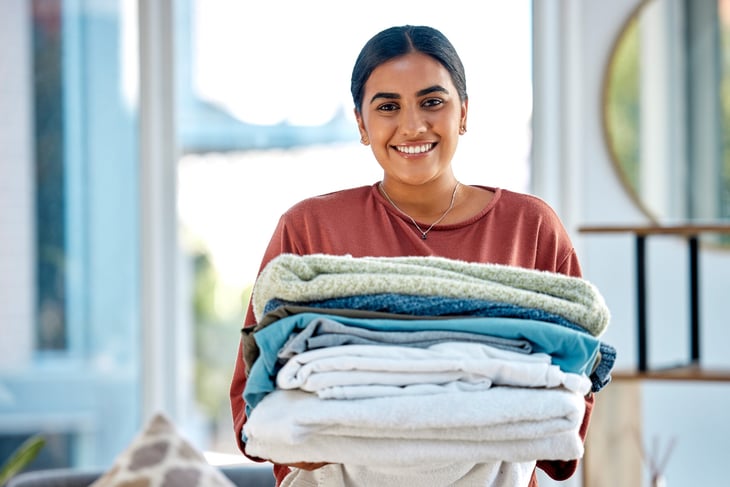 Happy woman holding clean, folded laundry