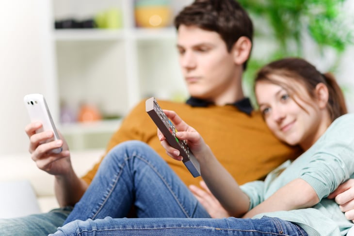 Couple watches TV while it's on their phones