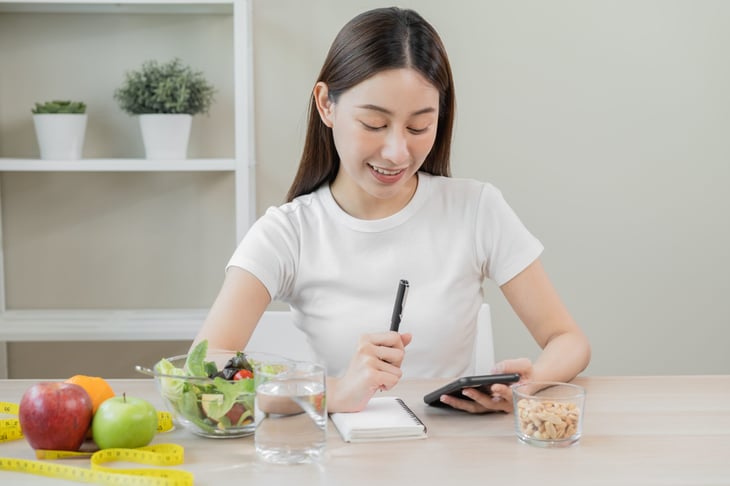 Woman using her phone while eating a healthy diet