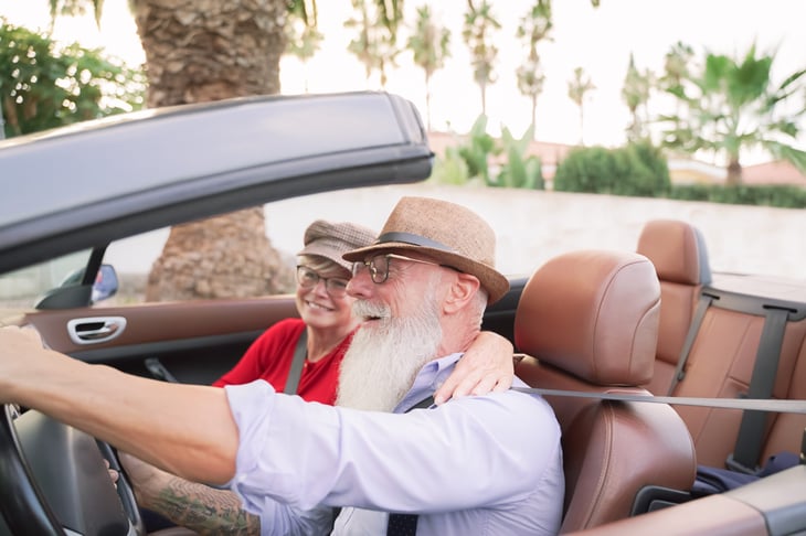 Wealthy retired senior couple and driving convertible car on vacation