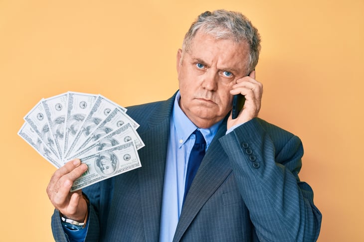 Upset businessman holding money