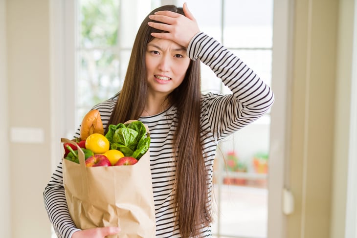 Woman upset holding groceries
